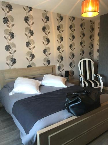 a bedroom with a bed with a black blanket and a chair at Maison d'hôtes La Colombelle in Colombé-le-Sec