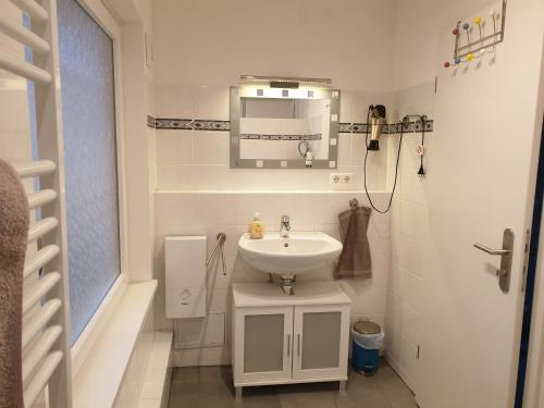 a white bathroom with a sink and a mirror at Ferienwohnung in Grenzach in Grenzach-Wyhlen