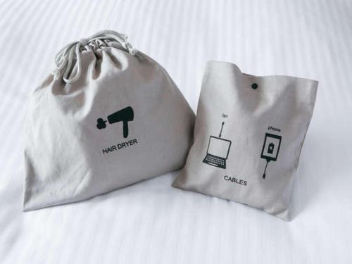 two white bags sitting on top of a bed at Fukuyama New Castle Hotel in Fukuyama