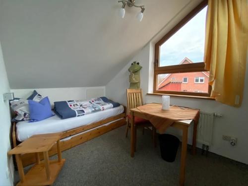 a bedroom with a bed and a table and a window at Ferienhaus Uferweg in Otterndorf
