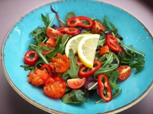 een blauw bord met een salade van tomaten en groenten bij Pergola Boutique Hotel in Boekarest