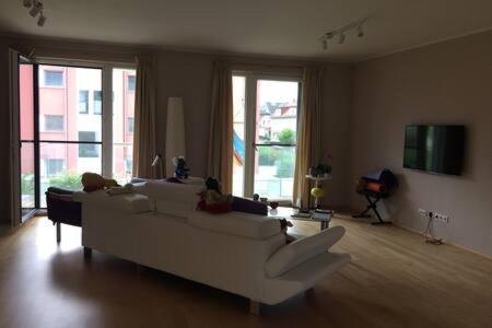 a living room with a white couch and windows at Stadtnähe und doch mitten in der Natur in Salzburg