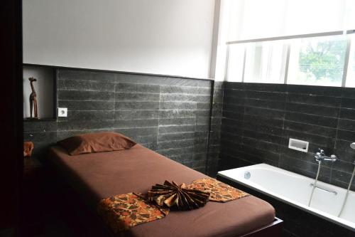 a bedroom with a bed and a tub and a sink at Grand Cakra Hotel Malang in Malang