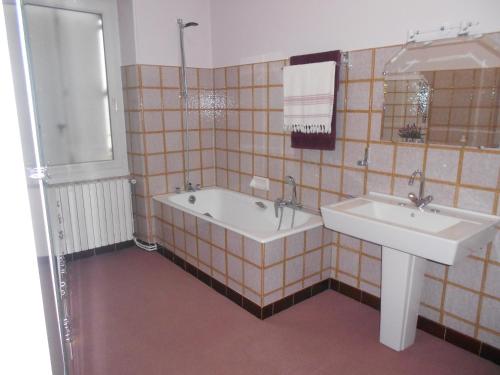 La salle de bains est pourvue de 2 lavabos, d'une baignoire et d'un miroir. dans l'établissement MAISON EN VILLE, à Airvault