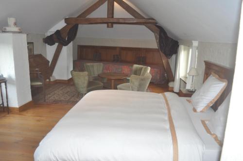 a bedroom with a white bed and a table and chairs at B&B Kasteelhoeve de Tornaco in Borgloon