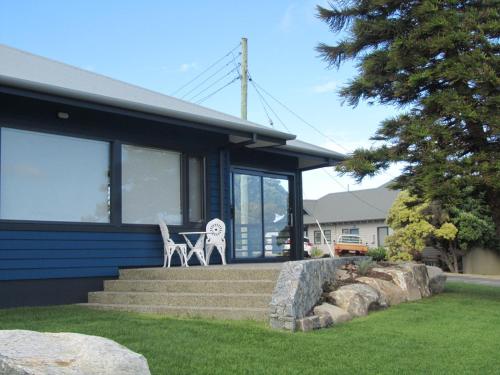 a blue house with a table and a white chair at Storm Bay Cottage in Augusta