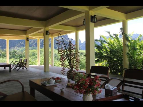 a porch with a table with flowers on it at Billion Views Khaosok Homestay in Khao Sok