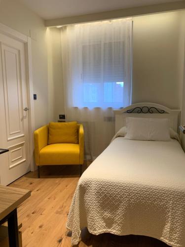 1 dormitorio con 1 cama y 1 silla amarilla en Hotel Boutique Astorga en Valladolid