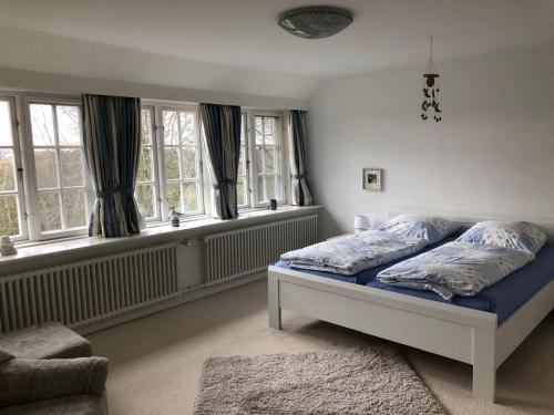 a bedroom with a bed with blue sheets and windows at Reethüs am Klintumer Moor in Leck