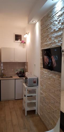 a kitchen with a tv on a stone wall at Studio Apartment Legcevic in Kaštela