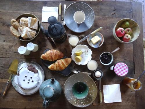 Una mesa de madera cubierta con platos de comida y postres. en L'escalier des rêves gîte, en Saint-Sauveur-en-Puisaye