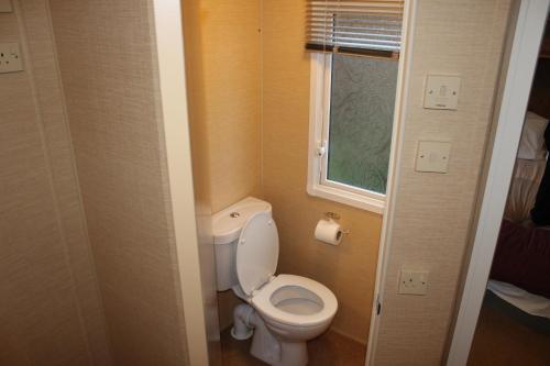 
a white toilet sitting next to a window in a bathroom at Port Haverigg Holiday Village in Millom
