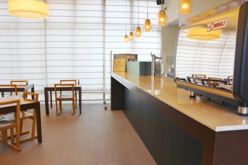 a restaurant with a counter and tables and chairs at Furano Natulux Hotel in Furano