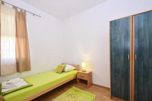 a bedroom with a green bed and a mirror at Apartment Luna in Tisno