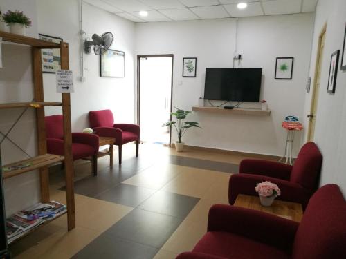 a waiting room with red chairs and a flat screen tv at Aban Transit House in Kuala Besut