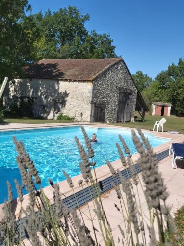 une piscine devant un bâtiment en pierre dans l'établissement Gîte Tissendie, à Bourg-de-Visa