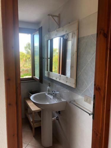 a bathroom with a sink and a mirror and a window at B&B Tavolara in Puntaldia