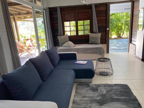 a living room with two beds and a blue couch at Le Goyav' appart avec piscine et jacuzzi au Vauclin in Le Vauclin