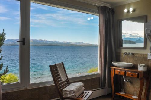 a room with a window with a chair looking out at the water at Sol del Nahuel - Hotel & Spa in San Carlos de Bariloche