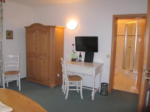 a room with a desk with a television and chairs at Land-gut-Hotel Lohmann in Drensteinfurt