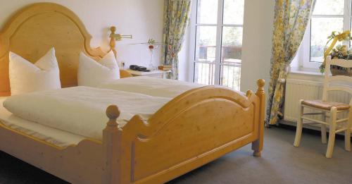 a bedroom with a large wooden bed with white pillows at Land-gut-Hotel Lohmann in Drensteinfurt