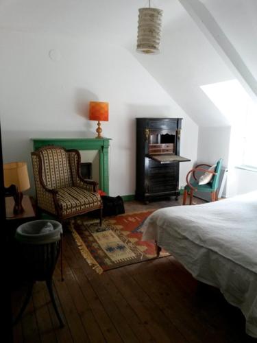 1 dormitorio con 1 cama, 1 silla y chimenea en Chambre d hôte chez Fany en Mur-de-Bretagne