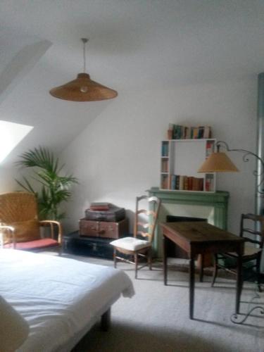 ein Wohnzimmer mit einem Tisch und einem Schreibtisch mit Stühlen in der Unterkunft Chambre d hôte chez Fany in Mûr-de-Bretagne