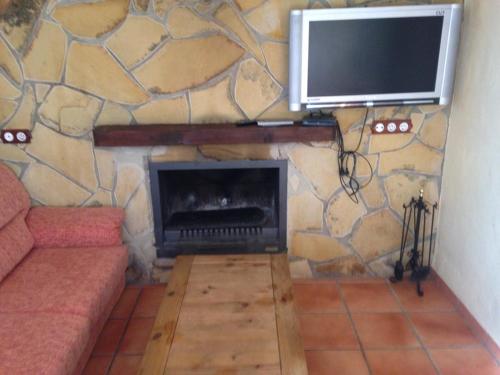 sala de estar con chimenea y TV en una pared de piedra. en Finca la sutilas, en Zahara de la Sierra