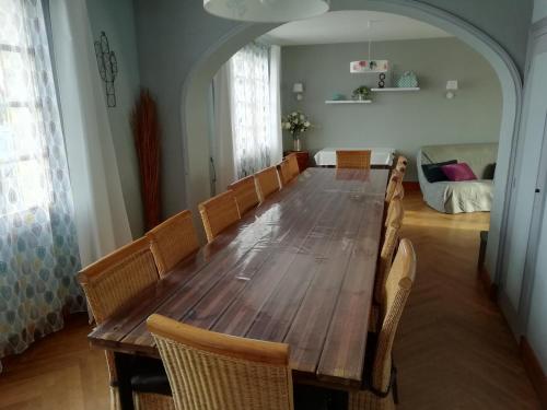 einen langen Holztisch in einem Zimmer mit Stühlen in der Unterkunft La Tribu de Beauval 6ch grand terrain et parking privé in Saint-Aignan