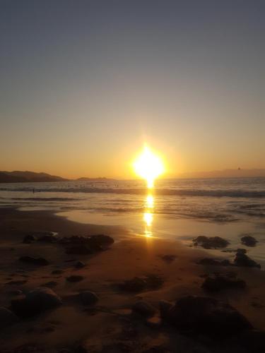 a sunset on a beach with the sun setting at Hosteria Piedra Blanca in Taltal