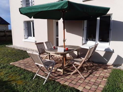 a table and chairs under a green umbrella at Les embruns in Plouarzel