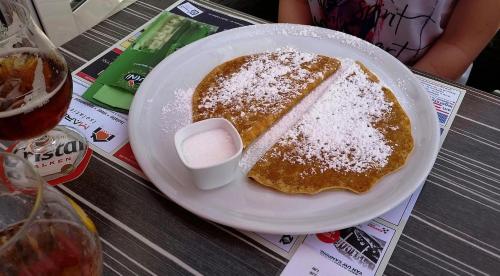 a plate of pancakes with powdered sugar on a table at Vakantiepark Wilhelm Tell Superieur Chalet in Oudsbergen 