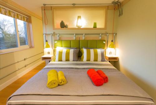 a bed with three different colored pillows on it at Claron Lodge in West Wittering