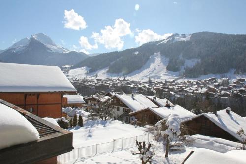 a snow covered village with a snow covered mountain at Résidence Julianna , trajets remontées mécaniques , livraison viennoiseries, piscine couverte in Morzine
