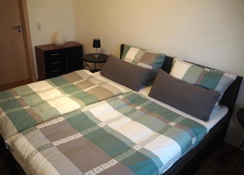 a bed with a plaid blanket and two pillows at Ferienwohnung am Kiessee in Breitungen