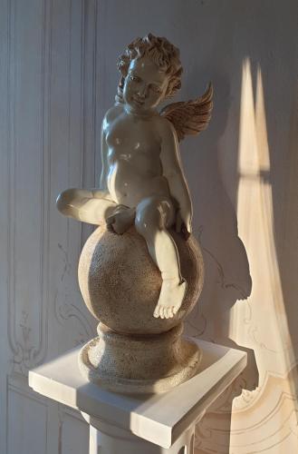 a statue of an angel sitting on a vase at La Villa des Arts in Savigné-lʼÉvêque