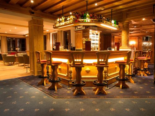 a bar in a restaurant with chairs around it at Hotel Karl Schranz in Sankt Anton am Arlberg