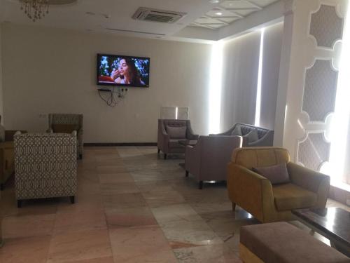 a waiting room with chairs and a tv on the wall at Kol Alayam Hotel in Makkah