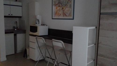 una pequeña cocina con 2 sillas y una barra en Studio Dijon Rue Pietonne, en Dijon