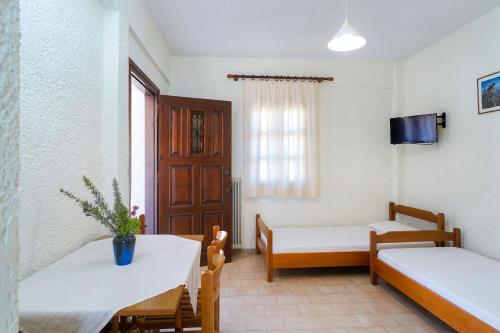 a room with two beds and a table and chairs at Kritikos Apartments in Pyrgadikia