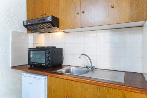 a kitchen counter with a microwave and a sink at Kritikos Apartments in Pyrgadikia