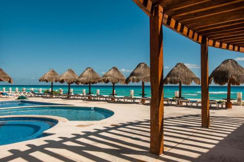 a resort with a swimming pool and umbrellas and the ocean at HotelZone L16 Beach Access in Cancún