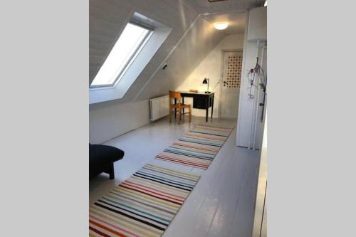 an attic room with a rug on the floor and a window at Holbæk. Byhus med fjordudsigt, og 5 min. til bymidten in Holbæk