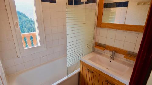 baño con lavabo, bañera y ventana en station valfréjus chavière, en Modane