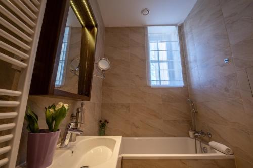 a bathroom with a tub and a sink and a mirror at Villa Meribel in Tatranská Lomnica
