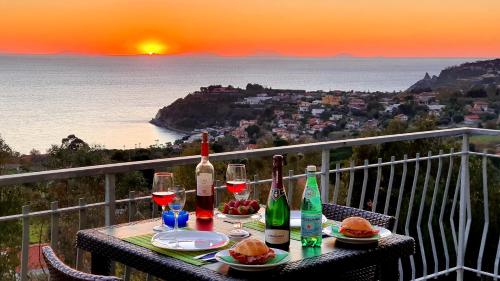 einen Tisch mit Weinflaschen und Gläsern auf dem Balkon in der Unterkunft NaturaMare Apartments - Piscina Idromassaggio con Vista Mare Aperta fino alle ore 22-00 in Capo Vaticano