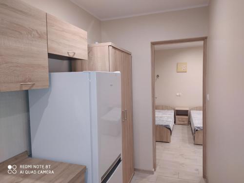 a small kitchen with a refrigerator and a bedroom at Dolistówka Apartamenty, pole namiotowe, balia z jacuzzi, ogród warzywny dla gości, plac zabaw dla dzieci in Goniadz