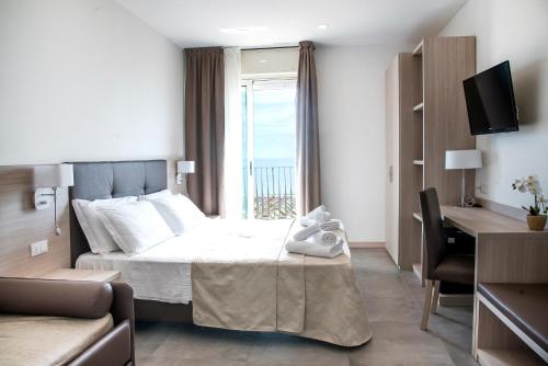 una camera con letto, scrivania e finestra di Hotel Solemare - Frontemare - 3 Stelle Superior a Lido di Jesolo