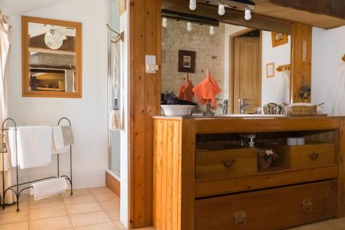 ein Badezimmer mit einem hölzernen Waschbecken und einem Spiegel in der Unterkunft Le Clos des Fayes in Berthegon