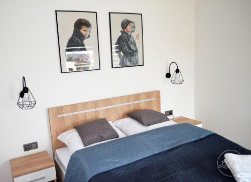 sypialnia z łóżkiem i 3 zdjęciami na ścianie w obiekcie MoKa Apartamenty Sianożęty w Sianożętach
